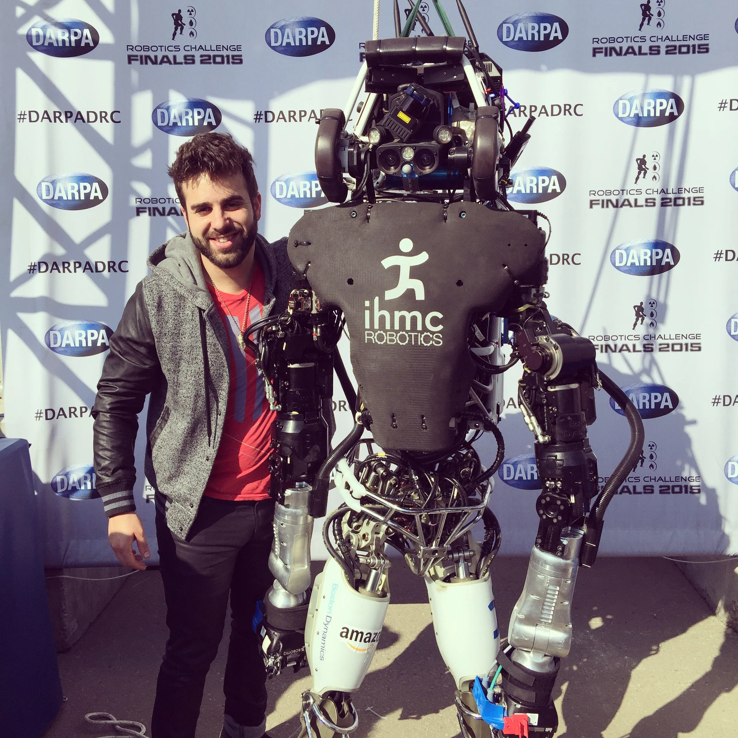Eric Matzner standing beside an IHMC robot at the 2015 DARPA Robotics Challenge Finals