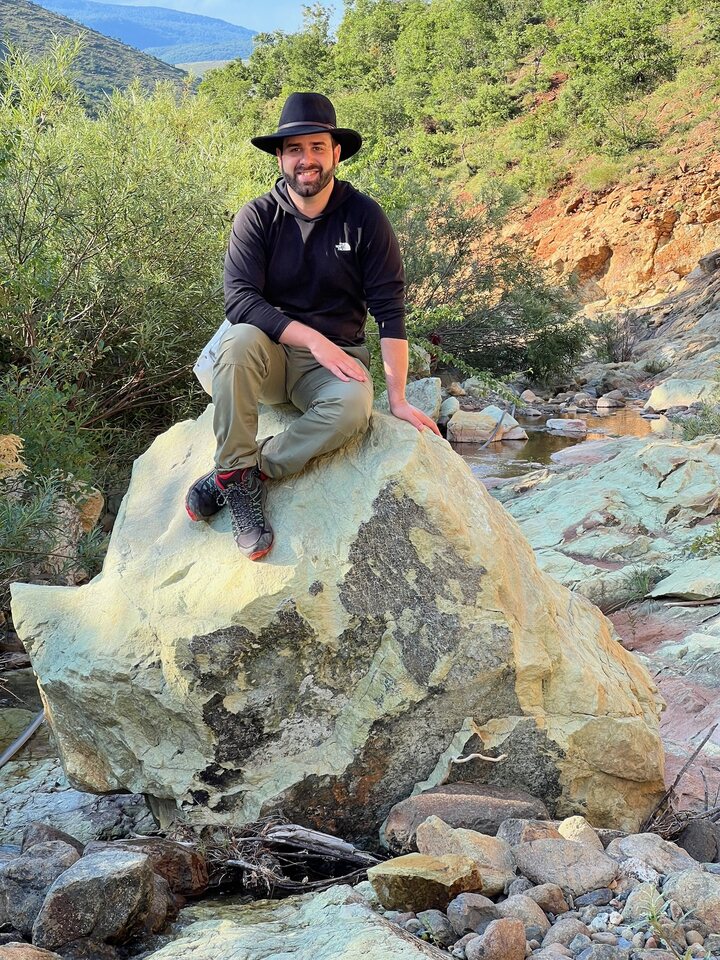 Eric Matzner sitting on a large olivine boulder